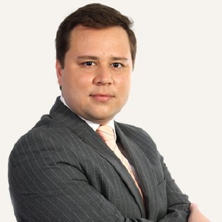 Felipe Asensi, de terno cinza e gravata, com os braços cruzados.